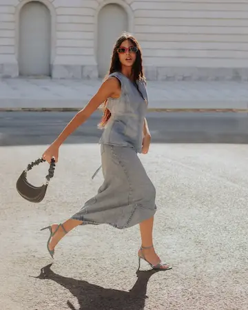 modelo en una plaza caminando con cartera en la mano